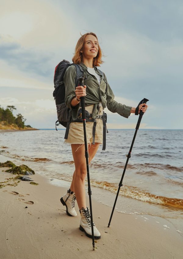 optimistic-traveller-using-walking-poles-during-beach-stroll