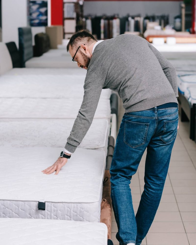 back-view-of-man-choosing-mattress-in-furniture-store