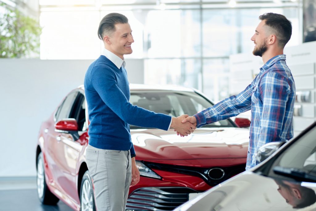 Car seller and customer handshake in car dealership