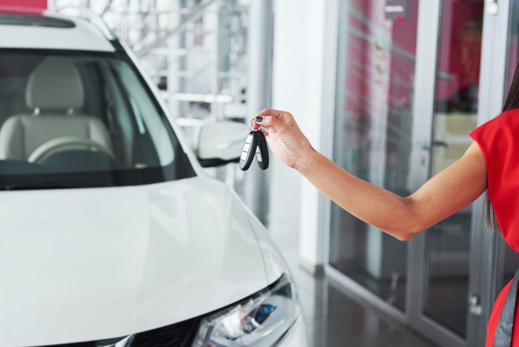 Cropped closeup of a car dealer holding out car keys to the camera copyspace car dealership
