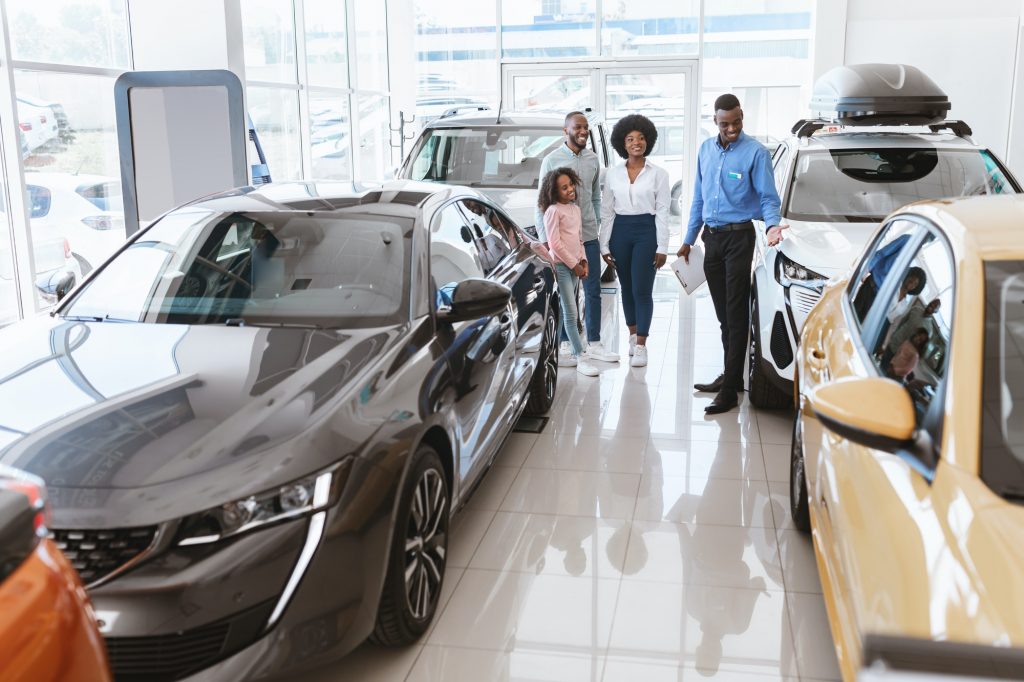 Friendly vehicle dealer offering black family selection of new cars at auto showroom