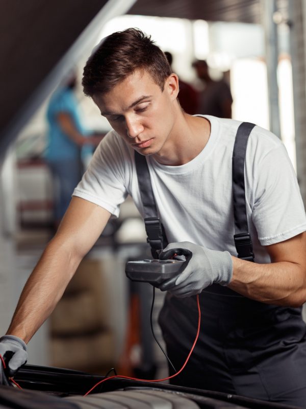 An attractive car mechanic is checking the results of his work at a car repair service