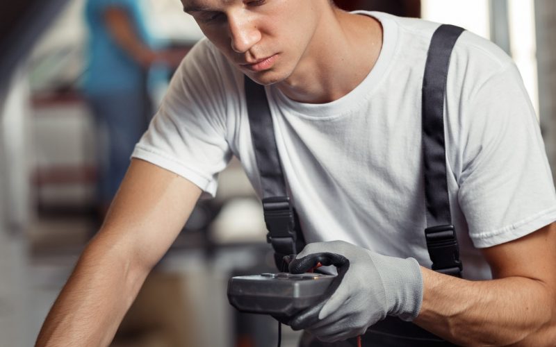 An attractive car mechanic is checking the results of his work at a car repair service