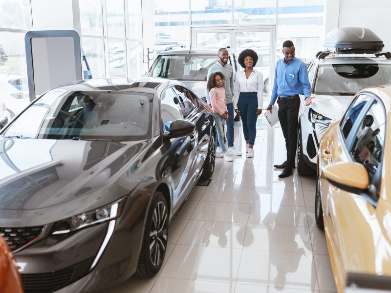 Friendly vehicle dealer offering black family selection of new cars at auto showroom