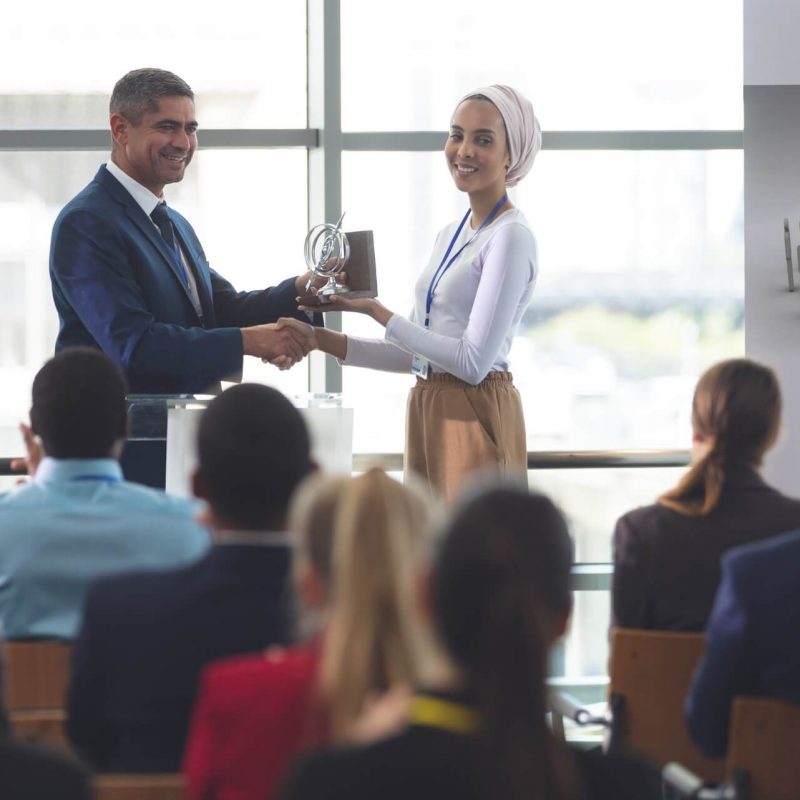 businesswoman-receiving-award-from-businessman-at-a-business-seminar-in-office-building