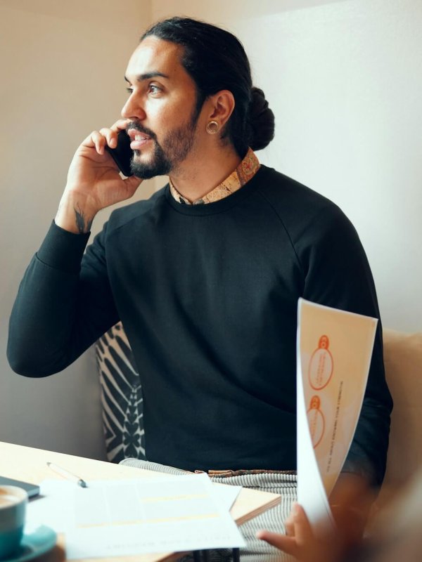 Home office, documents and phone call, freelancer man at desk consulting on smartphone with financi