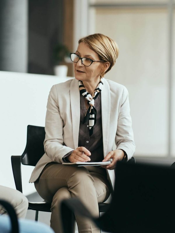Mature therapist talking to participants of group therapy at mental health center.