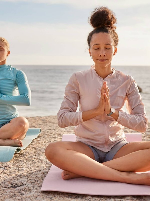 Yoga, meditation and friends outdoor on a beach together for mental health or wellness in summer. E