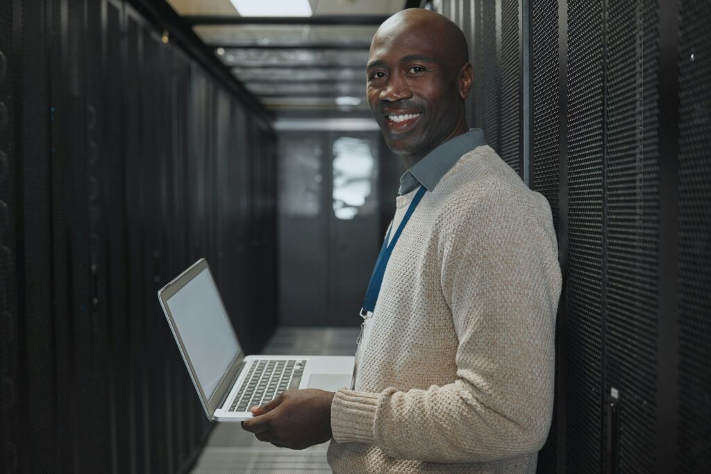 Server room, laptop and man portrait or technician for data center, system and cybersecurity code.